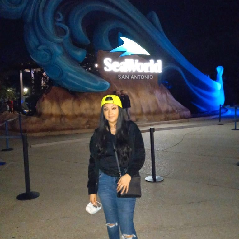 Person posing in front of a SeaWorld sign at night.