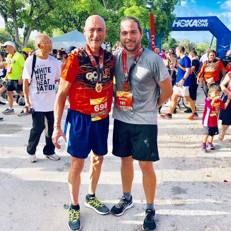 Two men posing at a lively outdoor event with a crowd in the background.