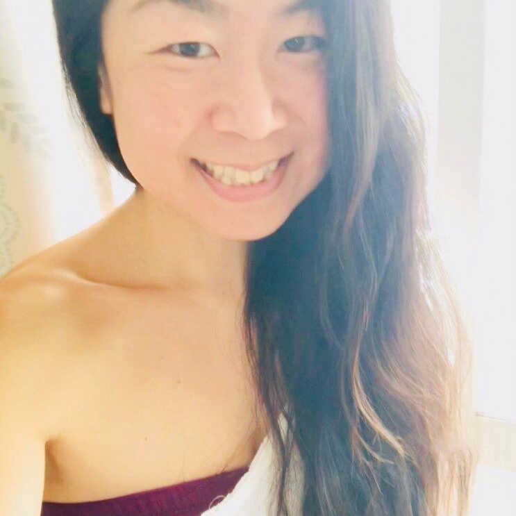 A smiling woman with long hair in soft natural light.