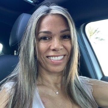 Smiling woman with long hair sitting in a car.