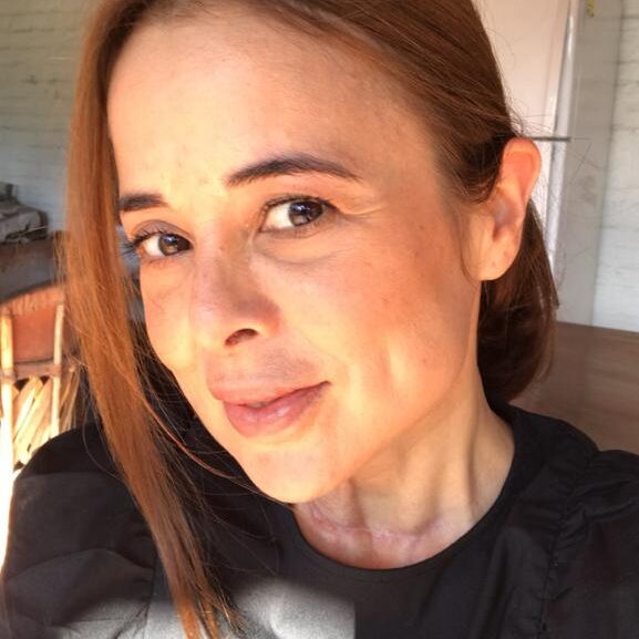 Close-up of a woman smiling warmly indoors.