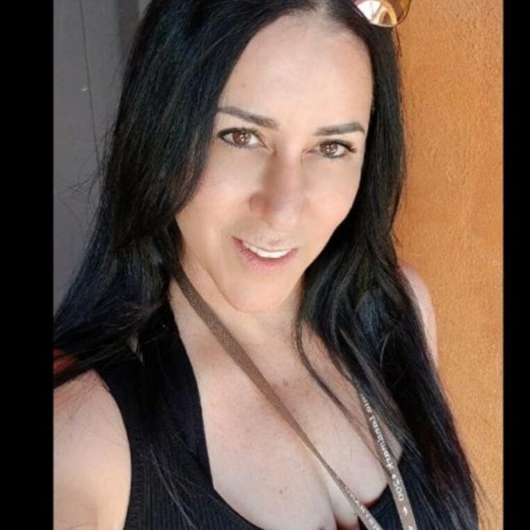 Smiling woman with long black hair and a casual necklace.